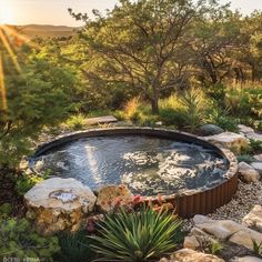 an outdoor hot tub surrounded by rocks and plants