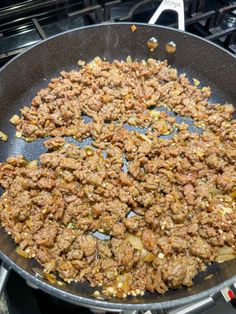 a frying pan filled with meat sitting on top of a stove