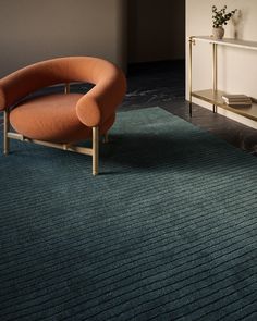 an orange chair sitting on top of a blue rug