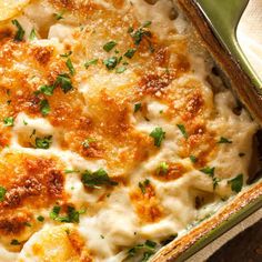 a casserole dish with cheese and parmesan on the top, garnished with fresh herbs