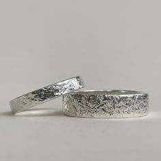 two wedding bands made out of silver with floral designs on the sides and one in white gold