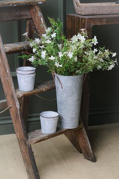 two buckets with flowers are sitting on an old steplade next to a ladder