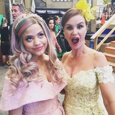 two women in dresses posing for the camera with one holding her mouth open and another wearing a tiara