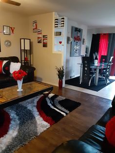 a living room with black leather couches and red rugs on the wooden floor