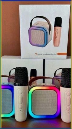 three different colored speakers sitting next to each other on top of a wooden table in front of a box