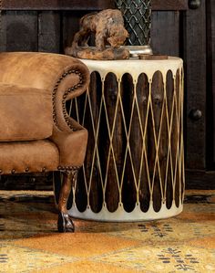 a brown chair sitting next to a table with a vase on it and a dog statue