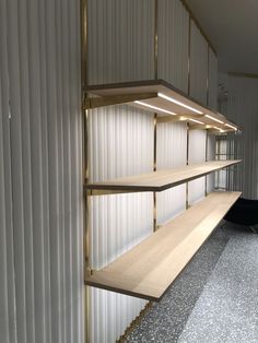 an empty shelf in the corner of a room with white walls and metal slats