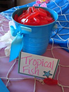 a blue bucket filled with gummy bears sitting on top of a pink table cloth