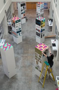 a person on a ladder working on an art project in a room filled with books