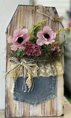 some flowers are placed in the pocket of a piece of wood that is made to look like an old pair of jeans