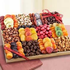 a wooden platter filled with assorted fruit and nuts