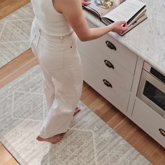 a woman standing in front of a kitchen counter with an open magazine on top of it