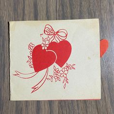 a piece of paper with two hearts on it sitting on top of a wooden table