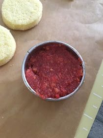 some food is in a metal bowl on a piece of paper next to two cookies