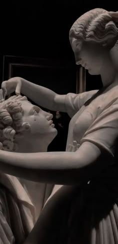 a statue of two women touching each other's hands in front of a mirror