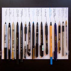 several pens and pencils lined up on a piece of paper with writing attached to them