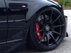 a black car with red brake pads parked on the street