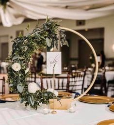 the table is set with plates and place cards for guests to sit at, along with greenery