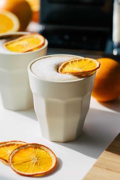 three cups with orange slices in them sitting on a table next to an orange slice