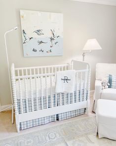 a baby's room with a white crib, blue and white bedding