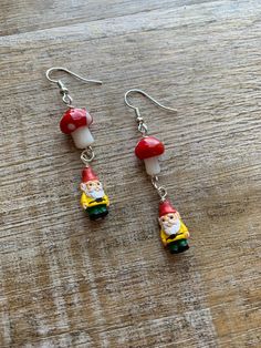 "Handmade cottagecore  gnome mushroom earrings 🍄 Regular Earrings- 2.25 inches long. (READY TO SHIP!) Tunnel Earrings- 2.75 inches long.  Clip On Earrings- 2.25 inches long. measurements are approximate.  Glass mushroom and ceramic gnome beads. Lightweight. These earrings are inspired by the \"cottagecore\" aesthetic, which romanticizes a simple and idyllic rural lifestyle. They can make a lovely addition to an outfit with a similar aesthetic or add a touch of whimsy to any ensemble." Charms For Earrings, Cottagecore Gnome, Tunnel Earrings, Elf Earrings, Ice Cream Shoes, Gnome Earrings, Christmas Purse, Elf Gnome, Cottagecore Earrings