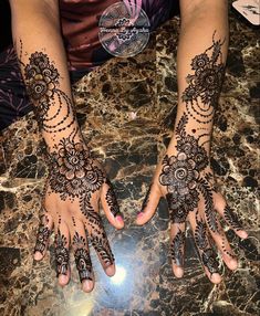 two hands with henna tattoos on them