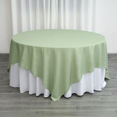 a round table with a green and white cloth on it, in front of a window