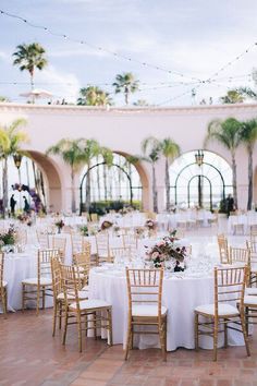 the tables are set with white linens and gold chairs for an elegant wedding reception