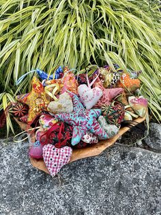 a basket filled with lots of different colored heart shaped ornaments on top of a rock