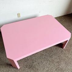 a pink table sitting on top of a carpeted floor