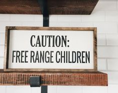 a sign that says caution, free range children on top of a shelf in front of a white brick wall