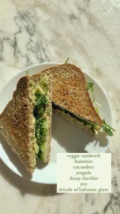 a sandwich cut in half sitting on top of a white plate next to a piece of paper