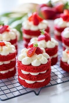 several red velvet cakes with white frosting and strawberries on top are sitting on a cooling rack