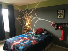 a bed room with a neatly made bed and spiderman wallpaper on the walls