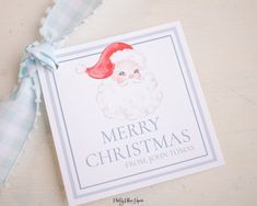 a merry christmas card with a santa clause on it's head and blue ribbon