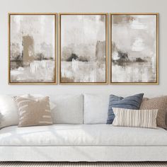 two paintings hang on the wall above a couch in a living room with pillows and throw pillows