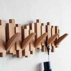 there is a coat rack made out of wood blocks and umbrellas hanging on the wall