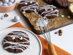 chocolate cookies decorated with googly eyes and white icing are on a plate next to an whisk