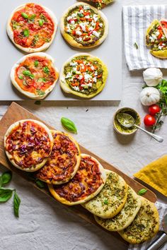 small pizzas with different toppings on a cutting board next to other food items