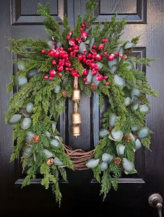 a wreath with holly, berries and bells hanging on a door