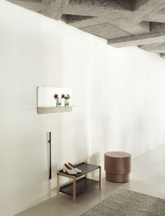 a white room with two vases on the wall next to a table and stool