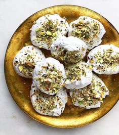 a gold plate topped with desserts covered in white frosting