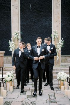 a group of men in tuxedos standing next to each other on a stone walkway