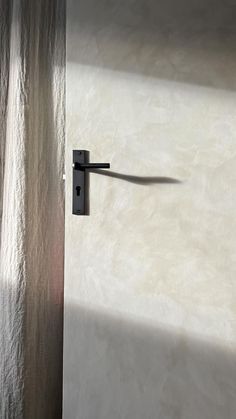 a door handle on the side of a white wall with light coming in from behind it