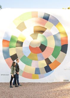 two people walking in front of a colorful wall