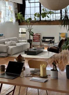 a living room filled with lots of furniture and plants on top of a wooden table