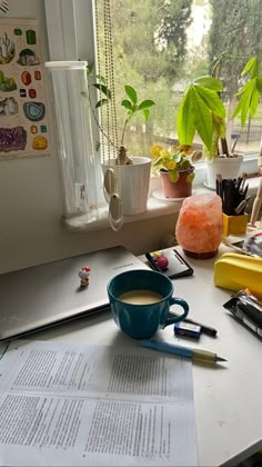 a cup of coffee sitting on top of a desk next to papers and pencils