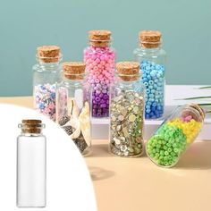 small glass bottles filled with different colored beads and corks on top of a table