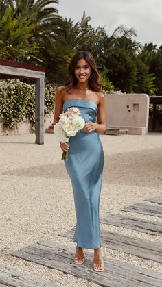 a woman in a blue dress holding a bouquet