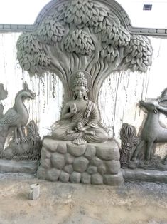 a statue of buddha sitting under a tree surrounded by other statues